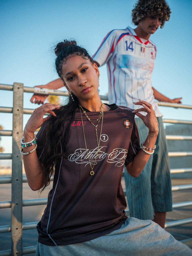 Maria Williams posing with layered gold chains in a BLRD jersey