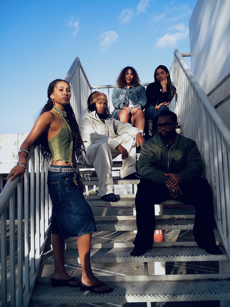 Maria Williams in a green halter and denim skirt on a stairway with the Gap cast