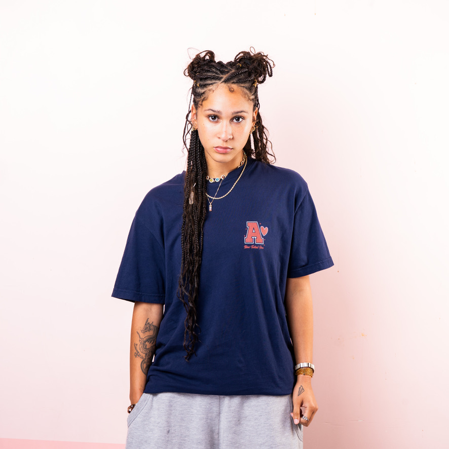 Maria Williams in a navy League of Legends Ahri tee against a pink backdrop